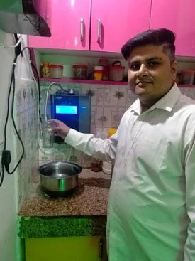 Individual with Chanson Quality Water Purifier demonstrating purified water